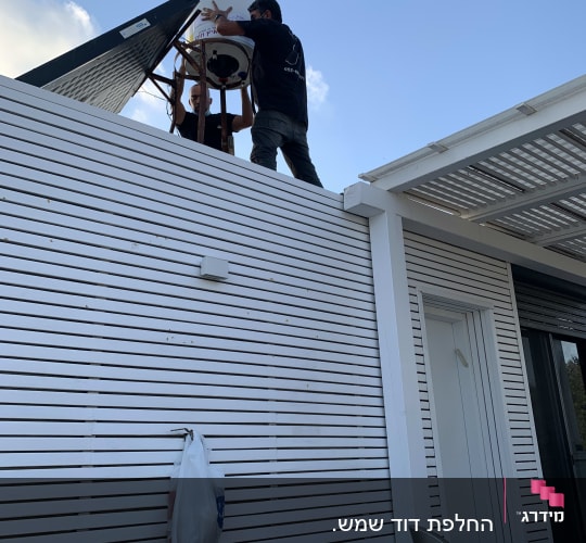 שני אנשים מתקינים דוד שמש על גג